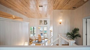 Un interior de madera con una escalera, una zona de comedor y un cartel con las letras 'RB'.