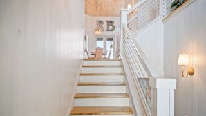 Una escalera con escalones de madera y barandillas blancas, que lleva a una puerta con 'RB' encima.