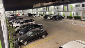 A parking lot with multiple cars and a building with green doors and white walls. - Palm Motel - Rosemead (Rosemead)