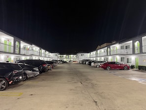 Un motel de varios pisos, un estacionamiento lleno de coches y un paseo central.