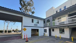 A building with a covered parking area, a 'SLOW' sign, and a 'NIGHT WINDOW' sign. - Palm Motel - Rosemead (Rosemead)