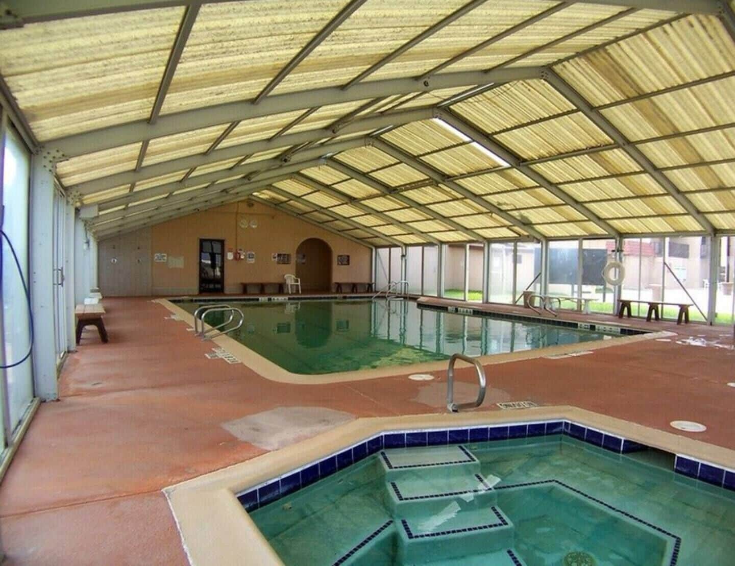 Une piscine intérieure dotée d’un sol carrelé et d’une structure de toit couverte.