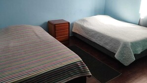 Une chambre avec deux lits, l’un recouvert d’une couverture à rayures et l’autre d’une couverture blanche unie.