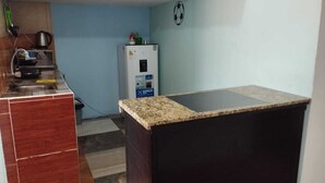 Une cuisine de taille réduite, dotée d’un plan de travail en granit, d’un réfrigérateur et d’un four à micro-ondes.