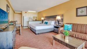 A hotel room with a bed, a sofa, a TV, a desk, and a kitchenette. - Oceanfront Sea and Sky Haven! (Myrtle Beach)