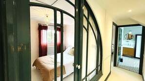A bedroom with a curved window, a bed, and a view into another room with a bathroom. - House 5 rooms 6 people, beach and port of Larmor nearby - wifi (LARMOR-PLAGE)