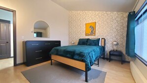 Une chambre à coucher avec un lit, une commode, un miroir et un tableau représentant une zèbre accroché au mur.