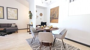 Un salon moderne comprenant un canapé, une table basse et un coin repas avec une table ronde et des chaises.
