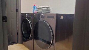 Une buanderie équipée de deux machines à laver à chargement frontal, d’une porte et d’un luminaire fixé au mur.