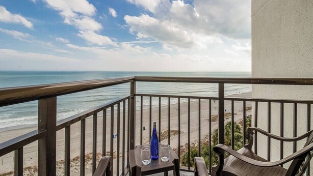 Un balcon avec vue sur la plage et l’océan.