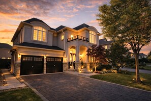 A large, two-story house with a garage, a balcony, and a well-maintained front yard. - 8BR Estate by Canterra Stays · Sleeps 20 · Games (Brampton)