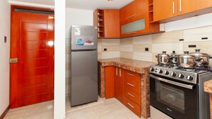 Una cocina con armarios de madera, un refrigerador de acero inoxidable, una estufa y un microondas.