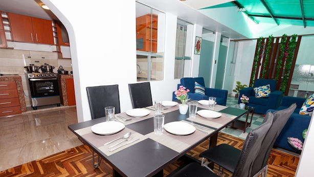 Una cocina moderna con horno integrado y comedor con mesa lista para cuatro.
