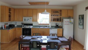 Una cocina con armarios de madera, una mesa de comedor con individuales y un refrigerador.
