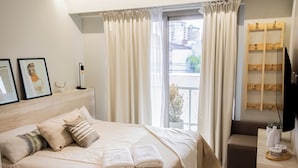 Una camera moderna con un letto grande, un comodino, una TV e vista sulla città.