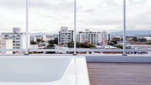 Una terrazza sul tetto con vista su un paesaggio urbano, che comprende edifici moderni e una catena montuosa in lontananza.