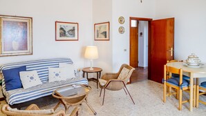 Una sala de estar con sofá, sillas, una mesa y una lámpara.