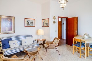 A living room with a sofa, chairs, a table, and a lamp.