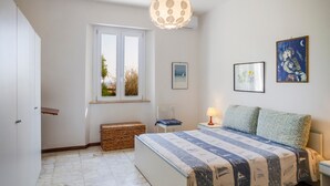 Un dormitorio con cama, ventana, mesita de noche, lámpara y decoración en la pared.