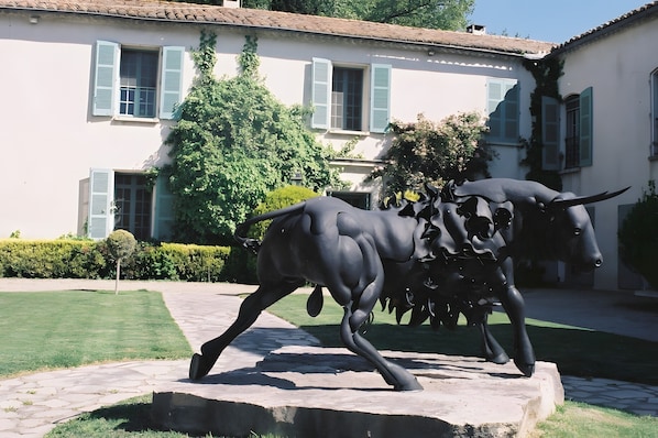 Une statue de taureau dans une cour, avec un bâtiment en arrière-plan.