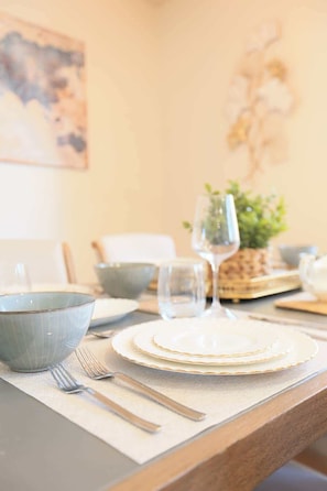 A dining table set with plates, bowls, and cutlery. - Rocky Mtn Escape-6 bdrm, near shops, dining, UofC (Calgary)