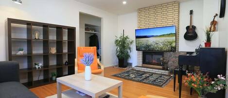 Un salon moderne avec une cheminée, un téléviseur, un piano et une bibliothèque.
