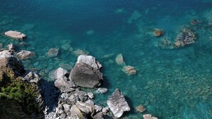 A rocky coastline with clear blue water and large boulders.