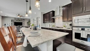 Une cuisine moderne avec des meubles de couleur sombre, un grand îlot central et des appareils électroménagers en acier inoxydable.