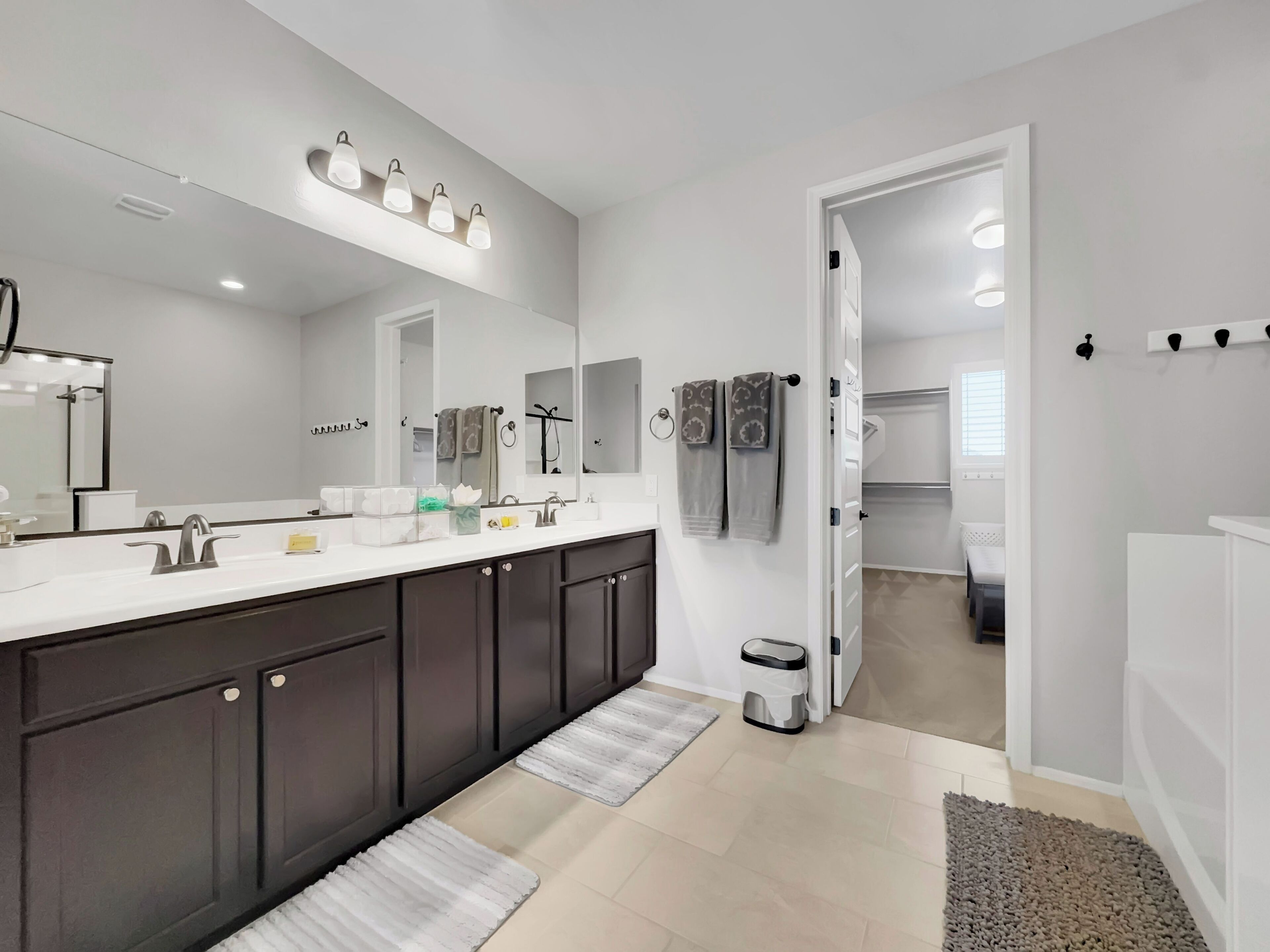 A modern bathroom with a large mirror, a double sink, and a walk-in shower.