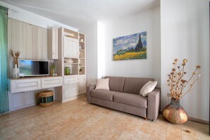A living room with a sofa, TV, cabinets, and a painting.