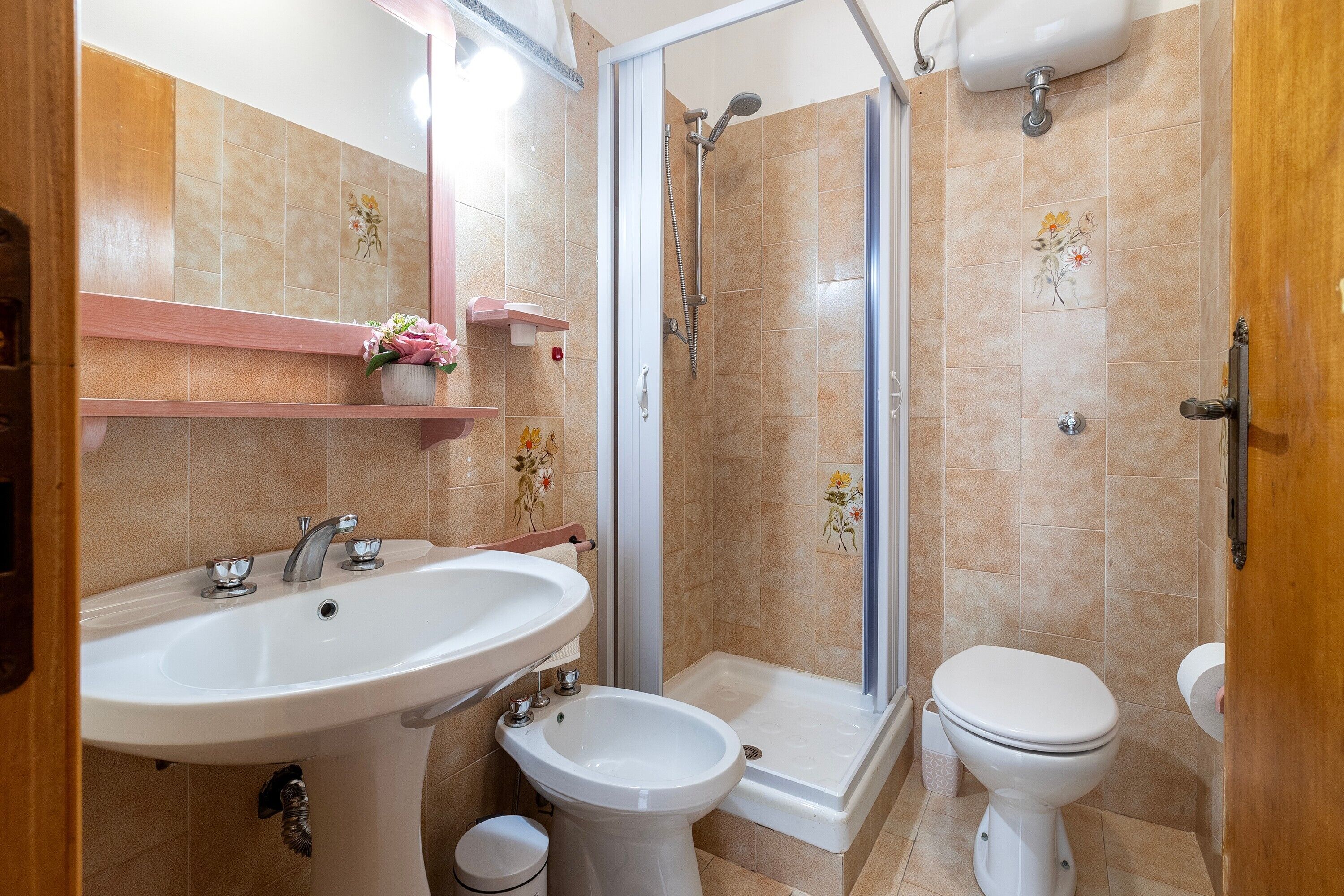 A bathroom with a sink, bidet, toilet, shower, and a mirror.