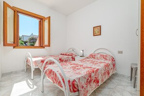 Una camera da letto con due letti, una finestra, un comodino e uno sgabello.