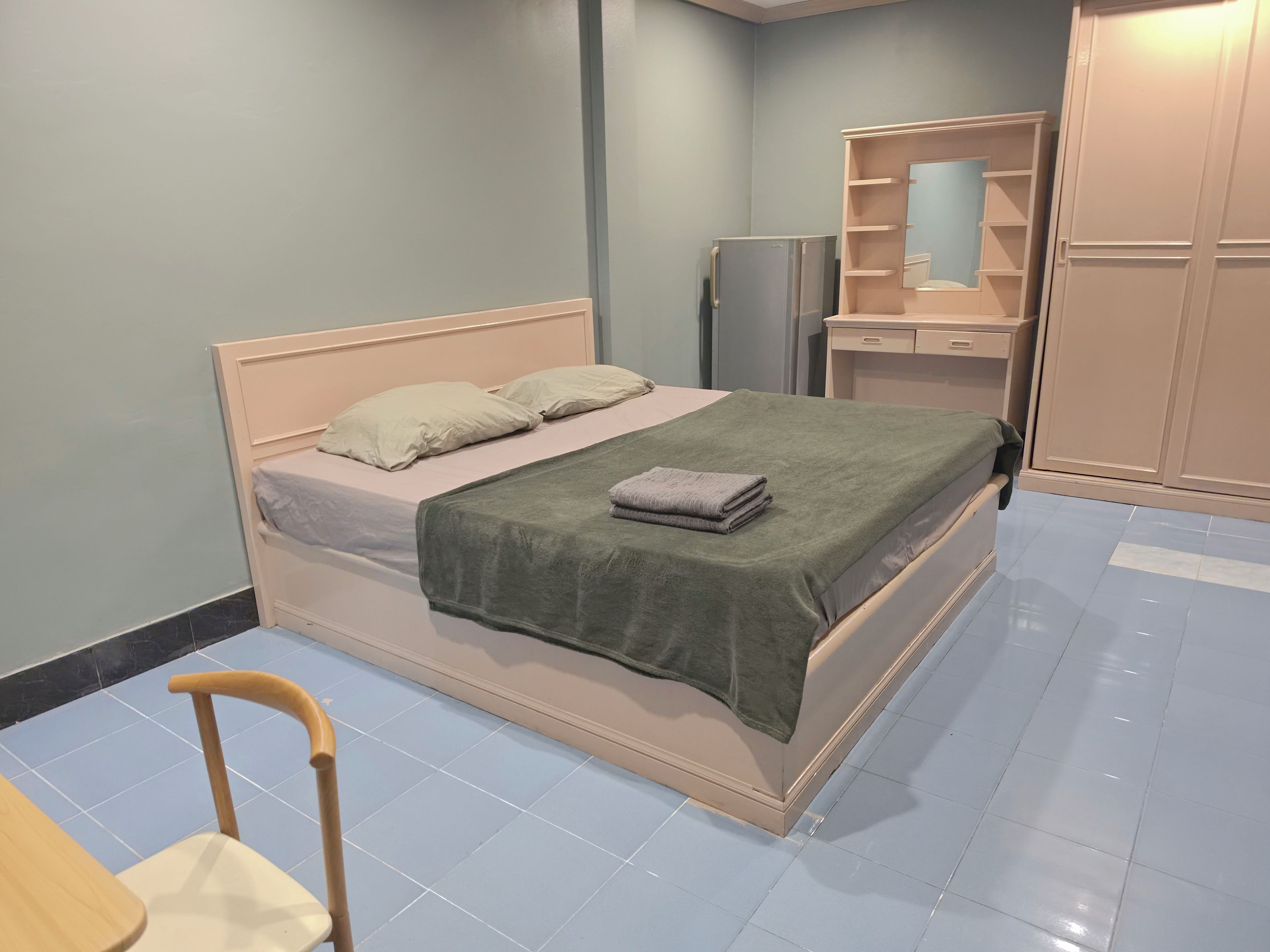 A bedroom with a bed, a chair, a wardrobe, and a mirror.