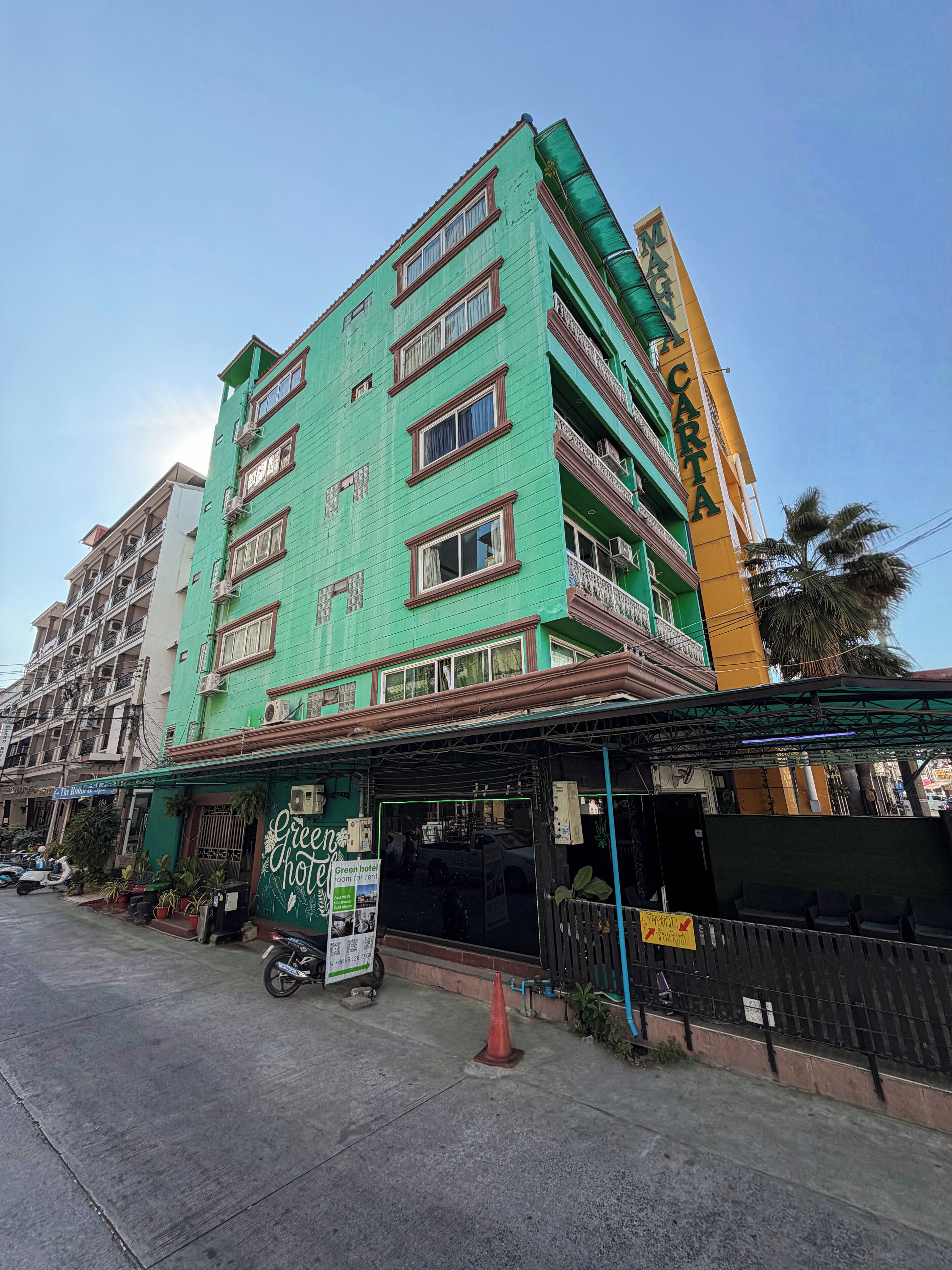 A multi-story hotel with a green facade and balconies.