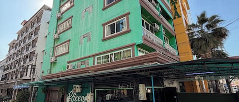 Ein mehrstöckiges Hotel mit grüner Fassade und Balkonen.