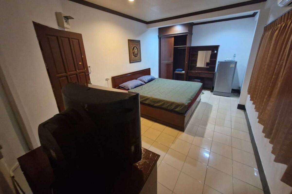 A hotel room with a bed, a television, a wardrobe, and a mirror.