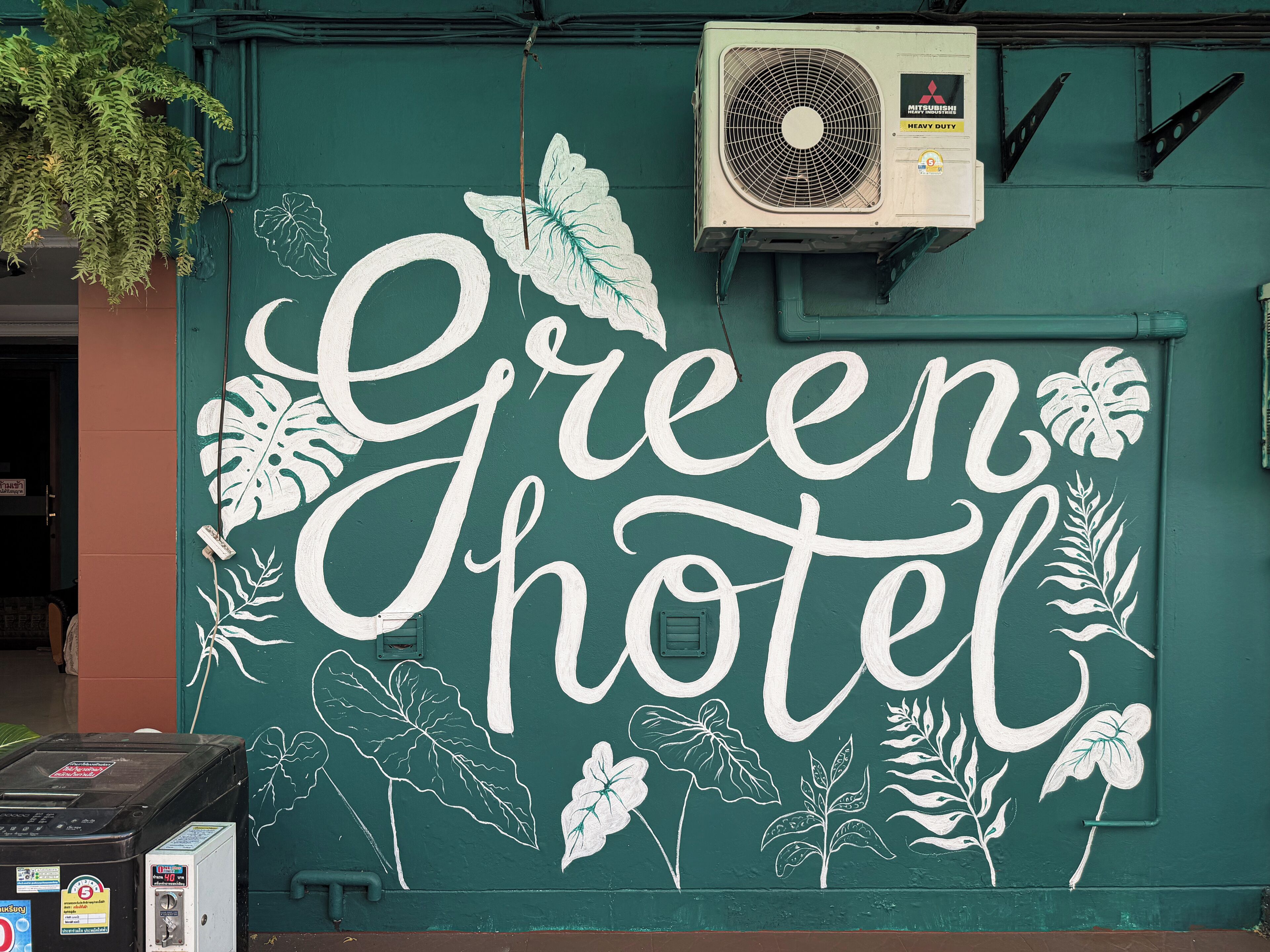 Una pared con el texto "Green Hotel" y diseños decorativos de hojas.