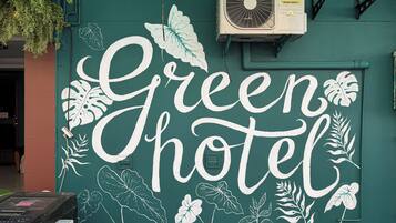 A wall with the text "Green Hotel" and decorative leaf patterns.