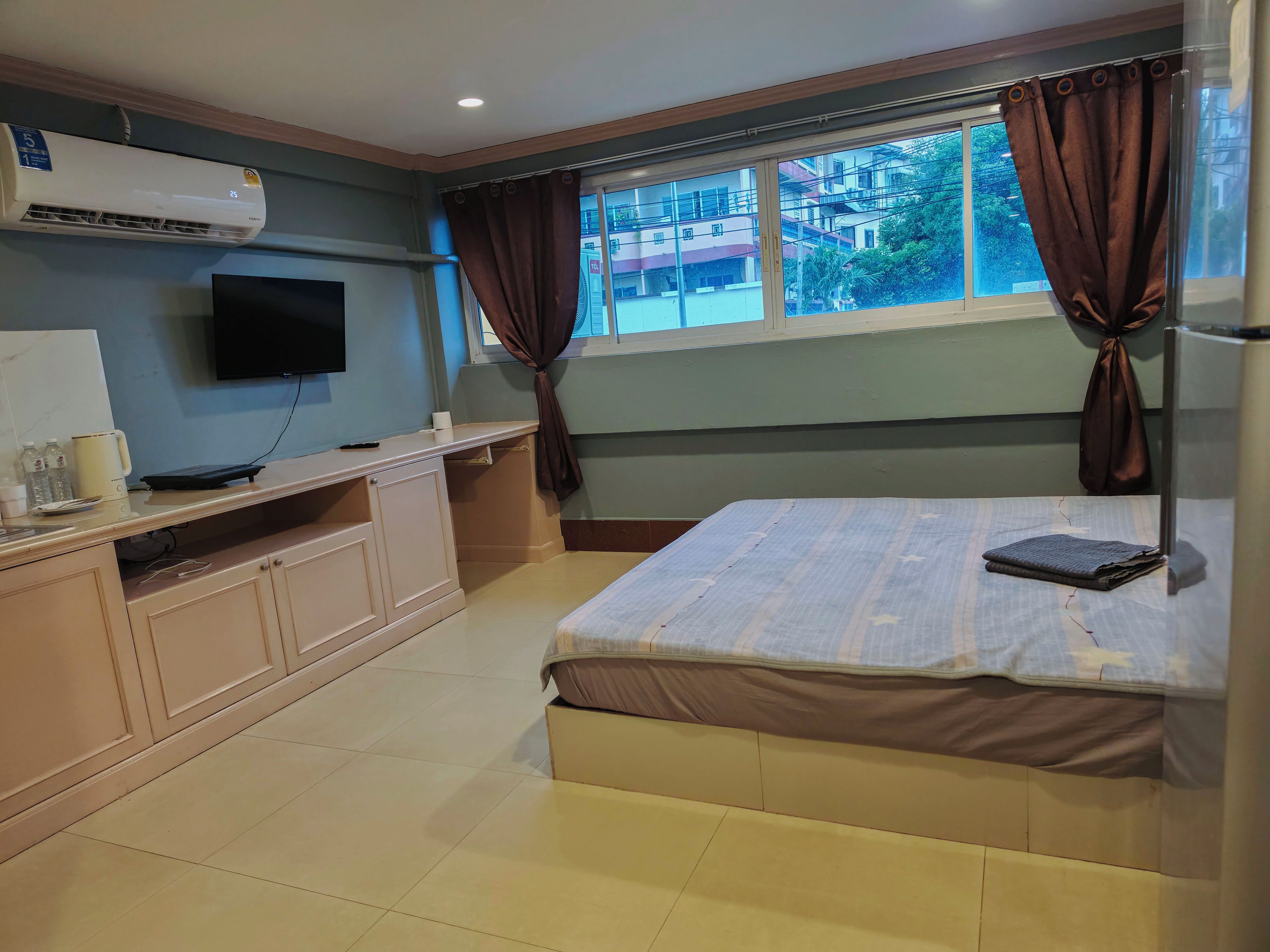 A hotel room with a bed, a desk, a television, and a window with curtains.