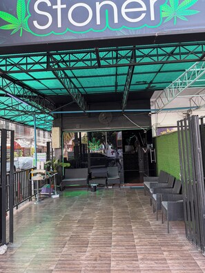 An outdoor seating area with wicker furniture and a green artificial turf wall. - Green Hotel (Pattaya)