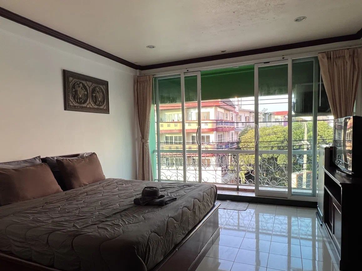 Ein Schlafzimmer mit einem großen Bett, einem Fernseher und einer Schiebetür zum Balkon.