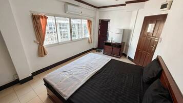 Habitación de hotel con cama, escritorio, silla, ventana con cortinas y puerta.