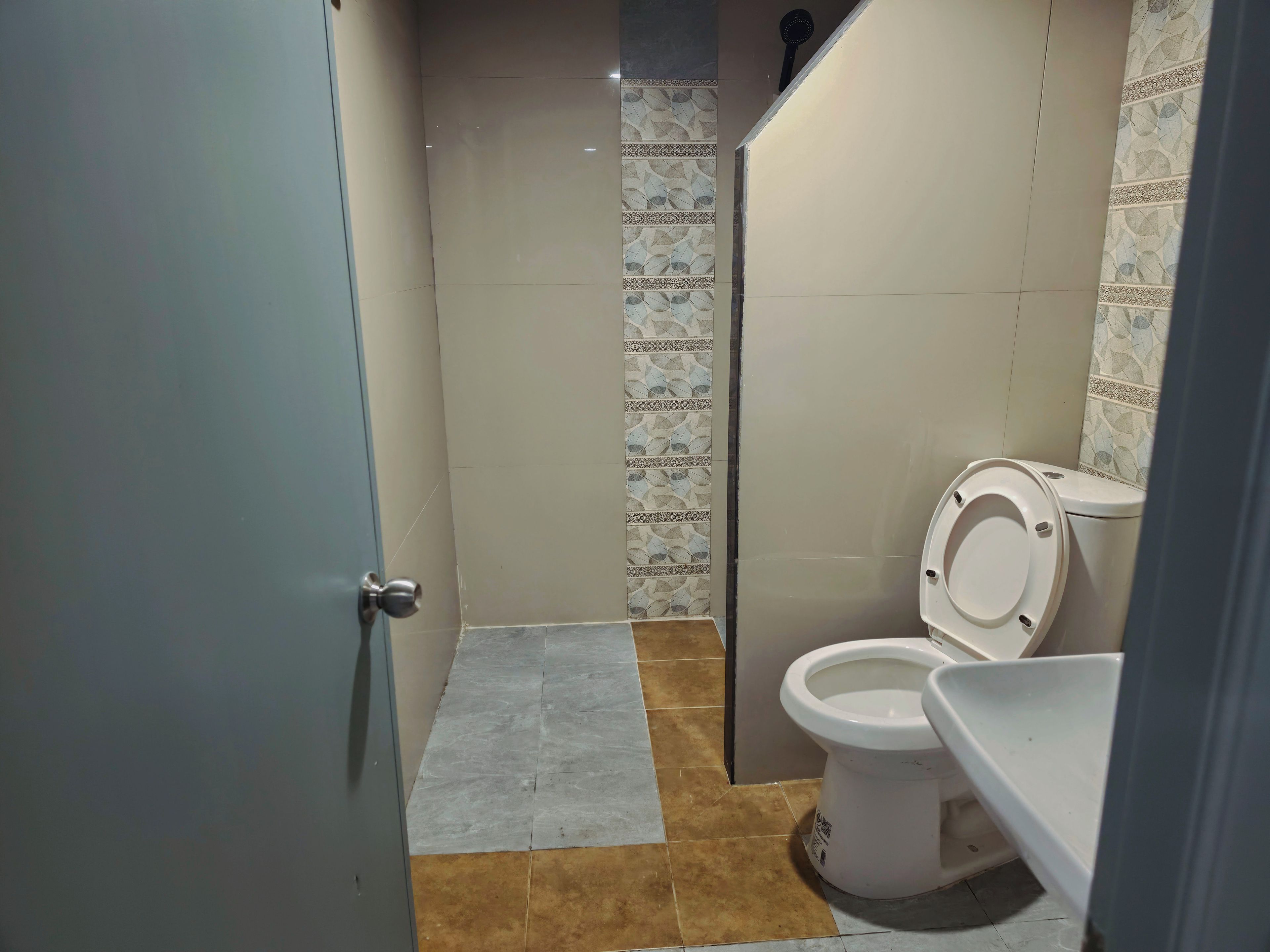 A bathroom with a toilet, a shower area, and a tiled floor.