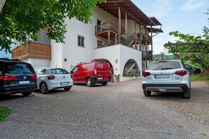 Ein Gebäude mit weißer Fassade, hölzernen Balkonen und einem Kopfsteinpflasterweg.