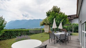 A deck with outdoor seating, a view of mountains, and a garden area. - Holiday Apartment 'Schwalbennest' with Mountain View, Wi-Fi and Air Conditioning (Appiano sulla Strada del Vino)