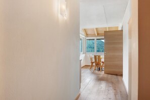Ein Gang, der zu einem Essbereich mit Holzboden und einem Tisch mit Stühlen führt.