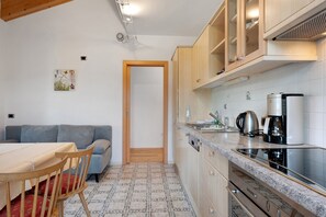 Une cuisine de taille réduite avec un coin repas, un canapé gris et un sol à motifs.