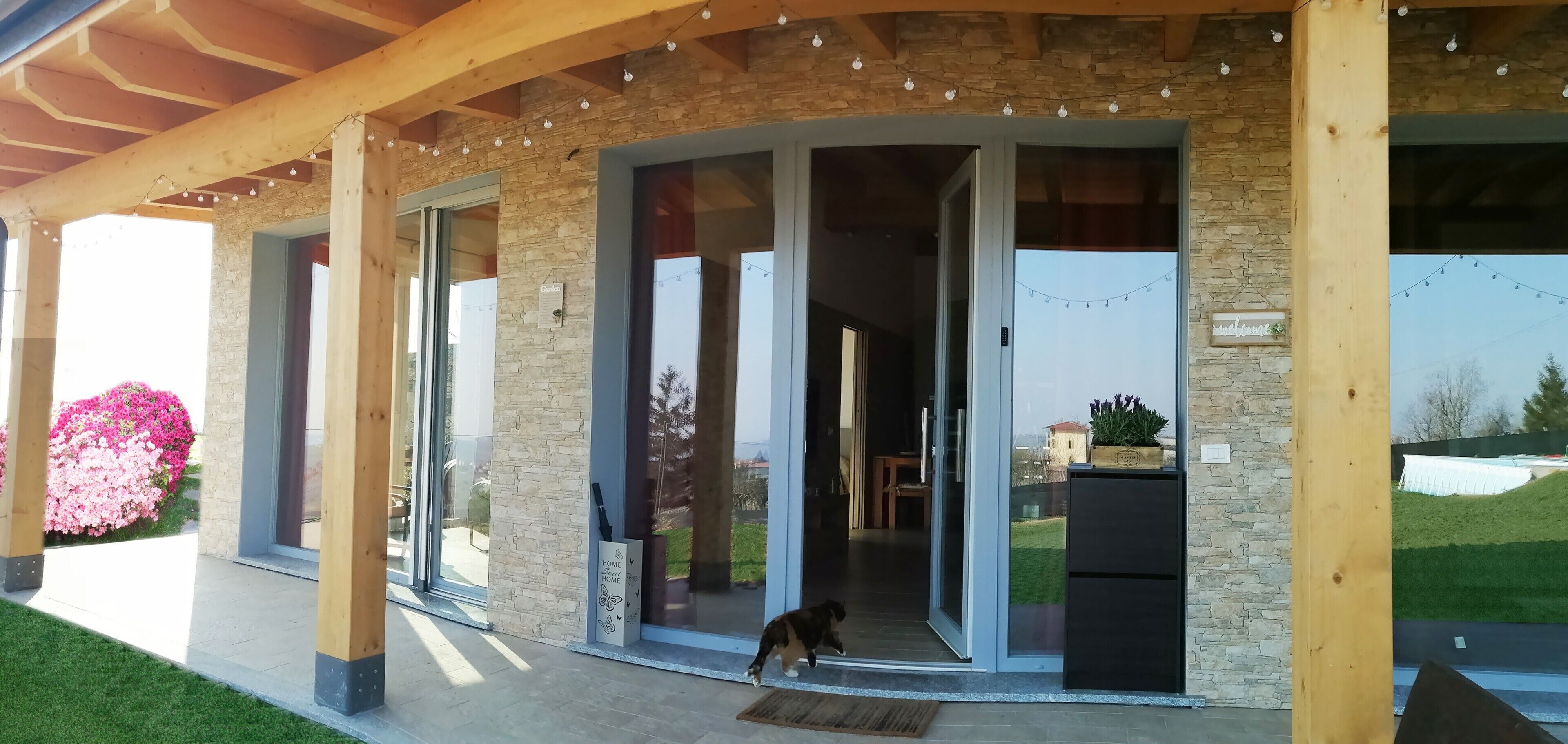A modern building with large glass doors, a stone facade, and a wooden porch.