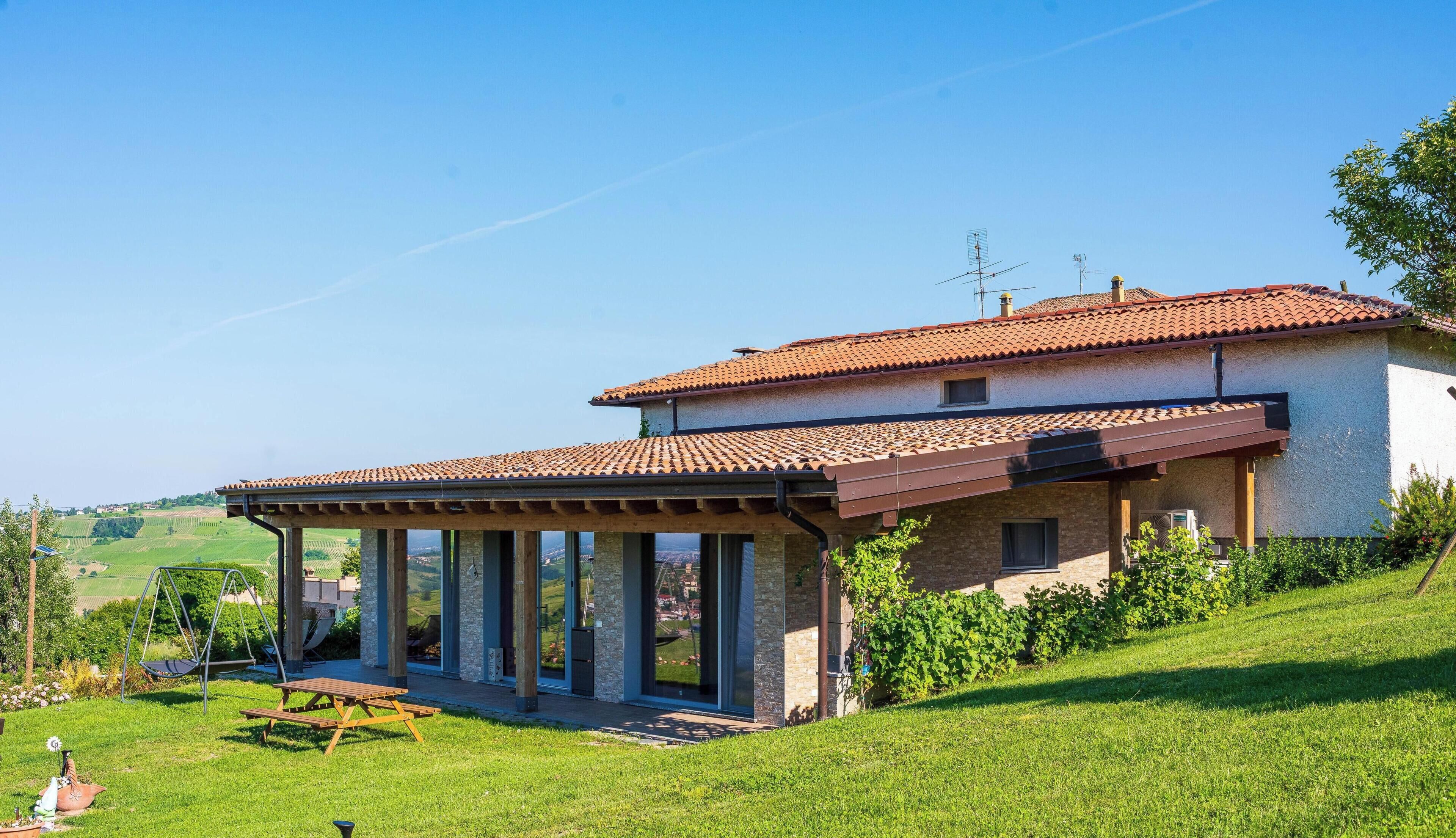 Une maison dotée d’un patio, d’un espace extérieur aménagé et couvert, et offrant une vue sur le paysage environnant.