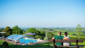 A couple sitting on a bench overlooking a swimming pool with a view of a vineyard and distant town. - Villa 'Elios' with Mountain View, Wi-Fi and Air Conditioning (Unknown)